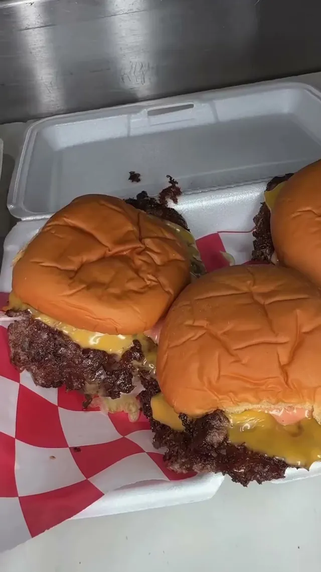 Three Mac sliders with American cheese and Juju sauce in a takeout box