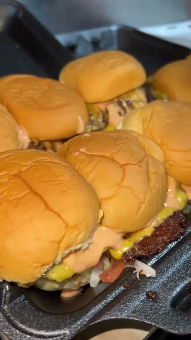 A row of freshly built sliders on the griddle